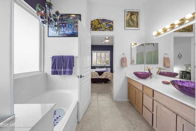 bathroom featuring vanity, tile patterned flooring, a bathing tub, and a healthy amount of sunlight