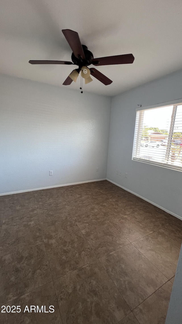 spare room featuring ceiling fan and baseboards