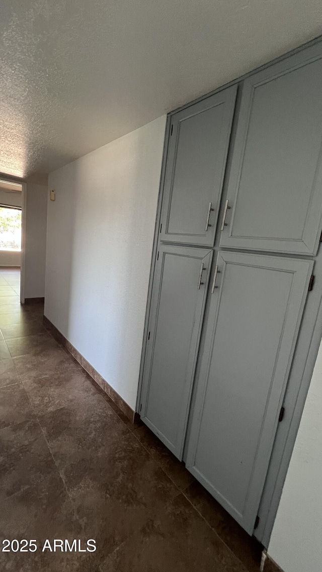 hallway with a textured ceiling and baseboards