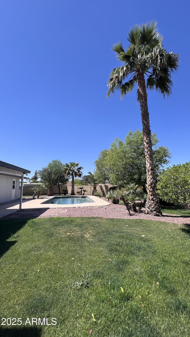 view of green lawn with an outdoor pool and a patio