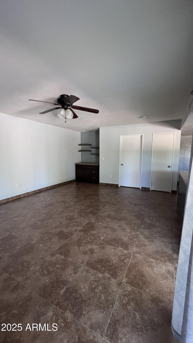 unfurnished living room featuring a ceiling fan and baseboards