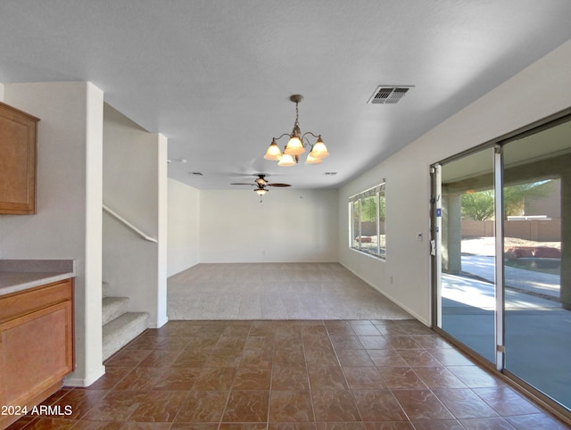 interior space featuring ceiling fan with notable chandelier and dark carpet