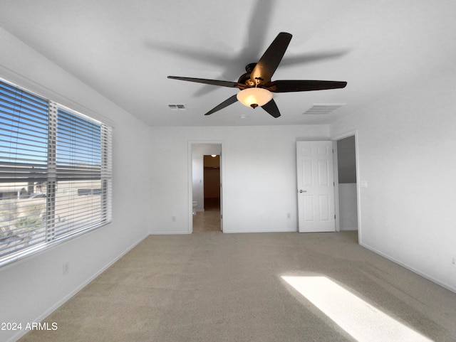 empty room featuring ceiling fan and light carpet