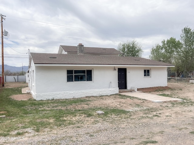 view of front of home featuring roof with shingles, fence, and stucco siding