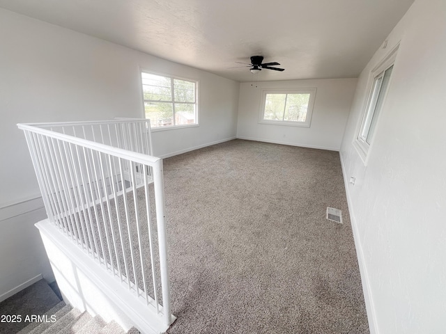 spare room featuring baseboards, a ceiling fan, visible vents, and carpet floors