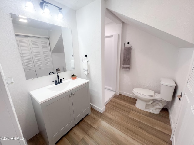 bathroom featuring toilet, vanity, wood finished floors, and baseboards
