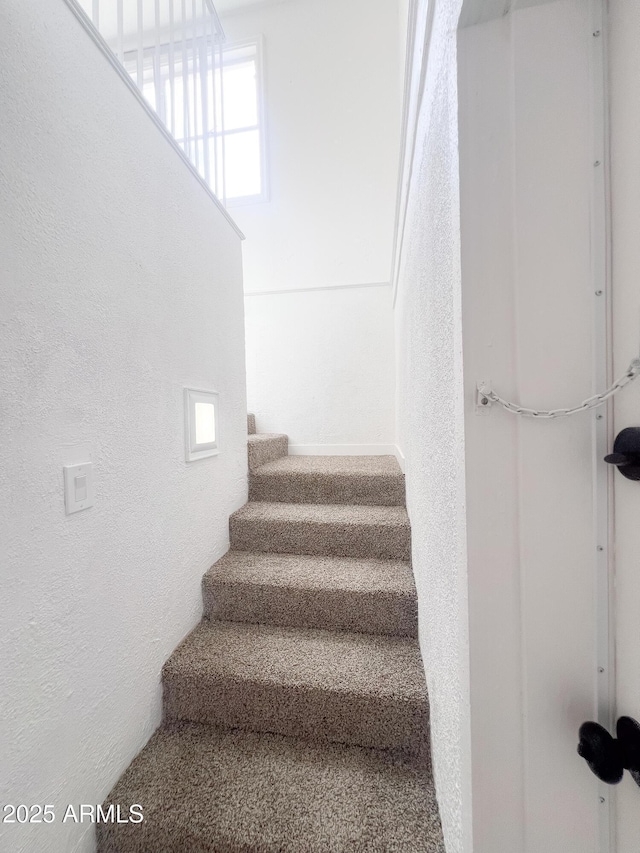 staircase featuring a healthy amount of sunlight and a textured wall