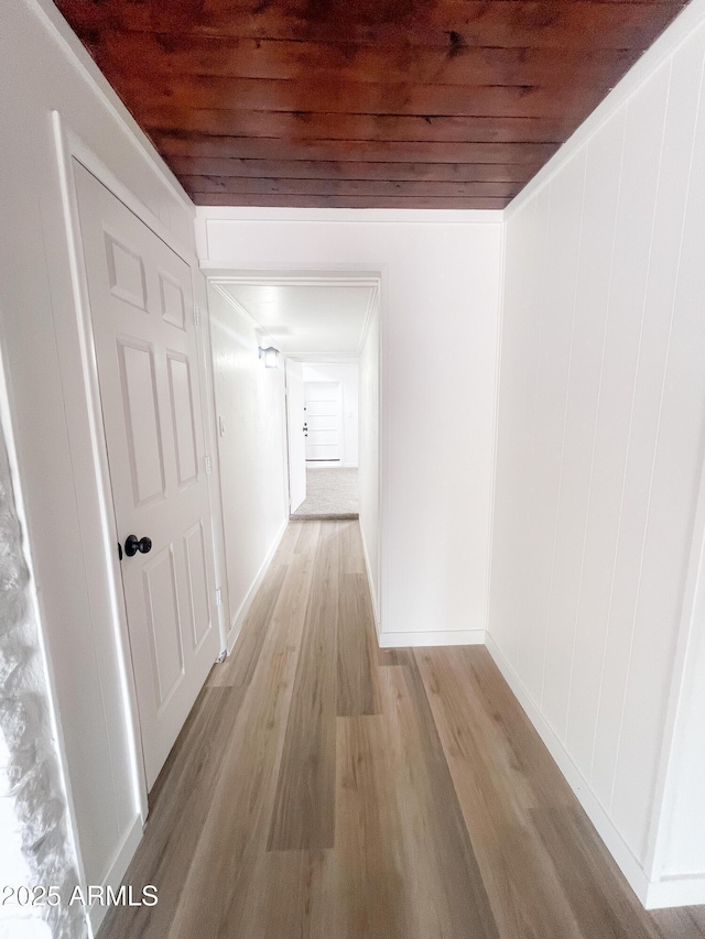 hallway with light wood finished floors and wooden ceiling