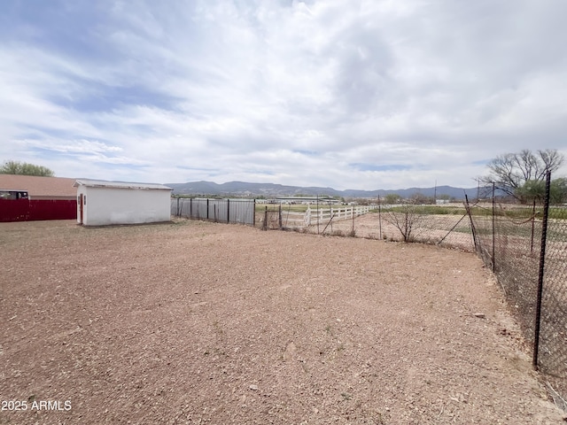 view of yard with an outbuilding, a mountain view, and fence