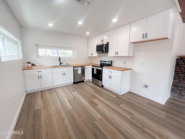 kitchen with light wood-style floors, wood counters, a sink, and appliances with stainless steel finishes