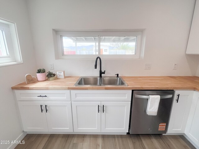 kitchen with butcher block counters, dishwasher, a sink, and white cabinets