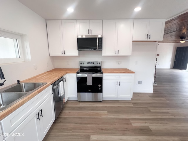 kitchen with wood counters, a sink, white cabinets, and stainless steel appliances