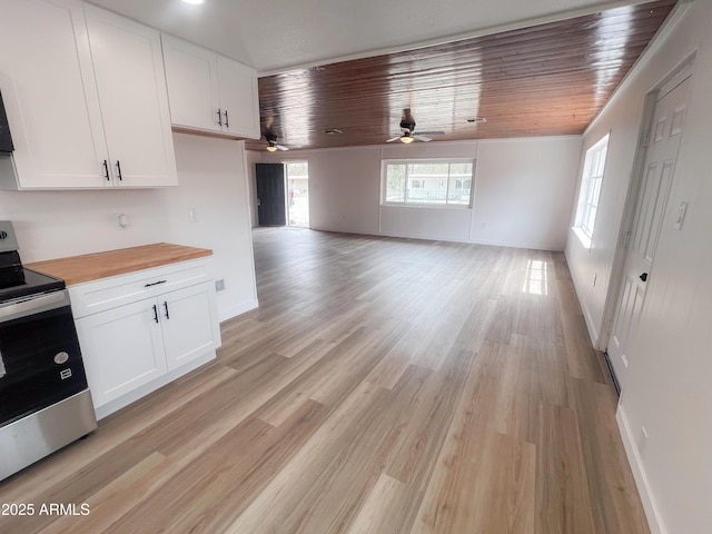 kitchen with stainless steel range with electric stovetop, wood counters, white cabinetry, and a ceiling fan