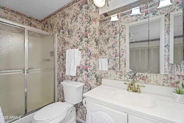 full bathroom featuring vanity, a shower stall, toilet, and wallpapered walls