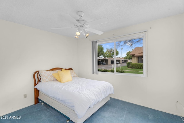 carpeted bedroom featuring ceiling fan and a textured ceiling