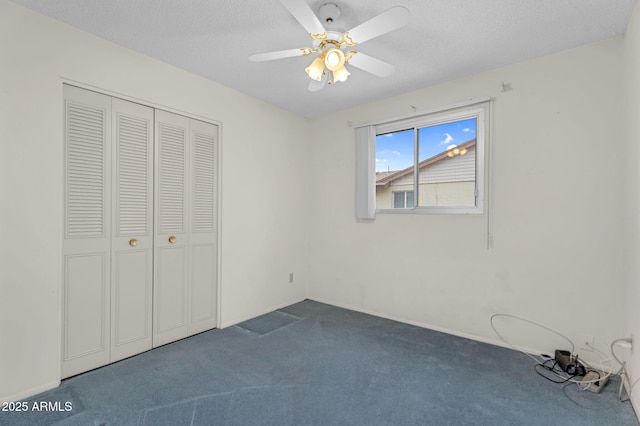 unfurnished bedroom featuring a ceiling fan, a closet, dark carpet, and a textured ceiling