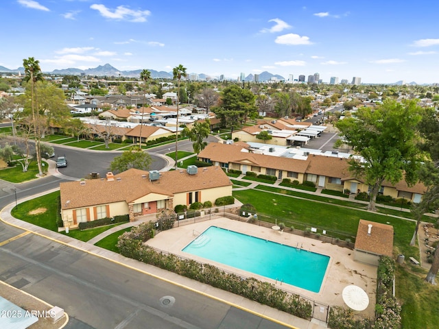 community pool with a patio, a residential view, fence, and a mountain view