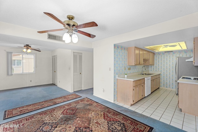 kitchen featuring light countertops, visible vents, white dishwasher, a sink, and wallpapered walls