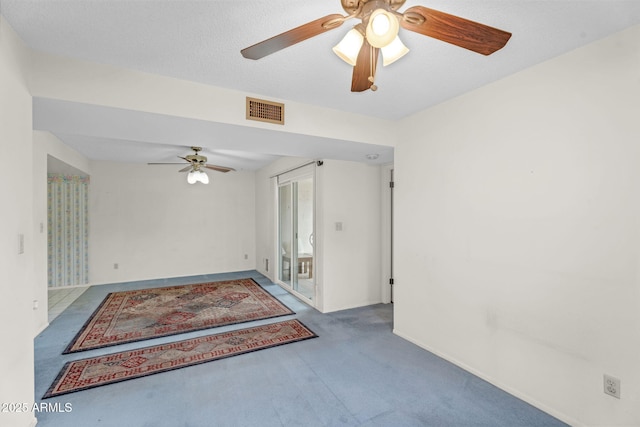 carpeted spare room with a ceiling fan, visible vents, a textured ceiling, and baseboards