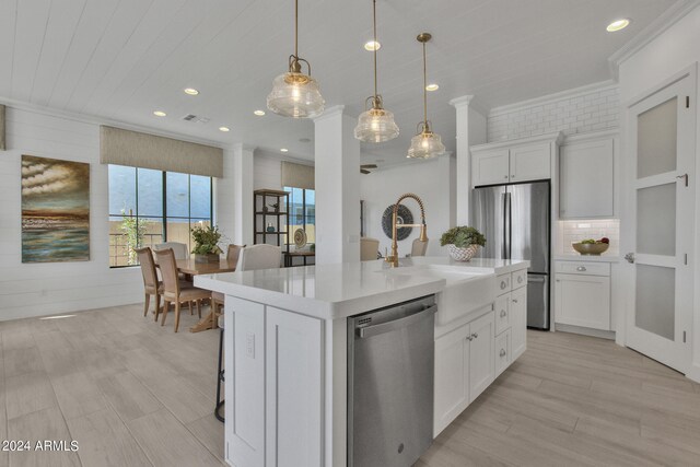 kitchen with white cabinets, an island with sink, pendant lighting, sink, and appliances with stainless steel finishes