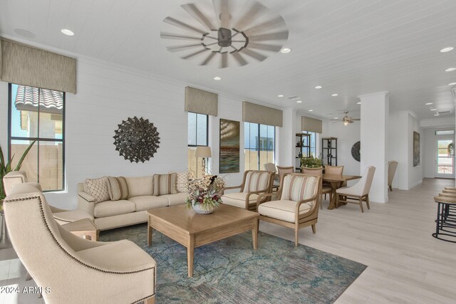 living room featuring ceiling fan, ornamental molding, and light hardwood / wood-style floors