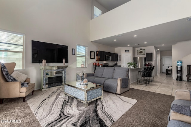 carpeted living room with a towering ceiling and a high end fireplace