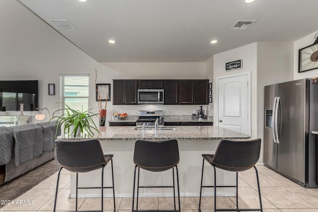 kitchen with appliances with stainless steel finishes, sink, light tile patterned floors, and an island with sink