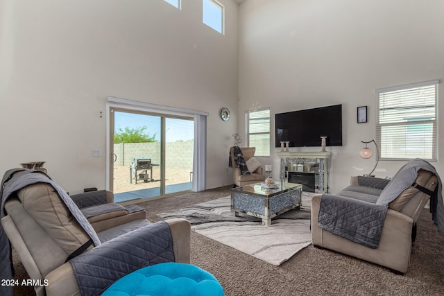 carpeted living room featuring a fireplace and a towering ceiling