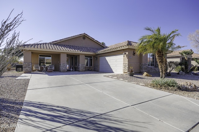 single story home with a garage, stone siding, a tile roof, and stucco siding