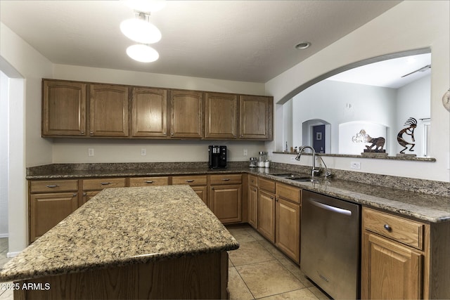 kitchen with sink, a kitchen island, light tile patterned floors, and stainless steel dishwasher