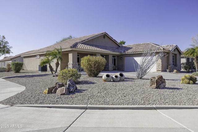 ranch-style home with driveway, stone siding, an attached garage, central AC, and stucco siding