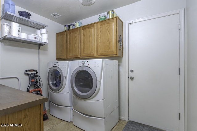 laundry room with cabinet space, light tile patterned floors, visible vents, and washer and dryer