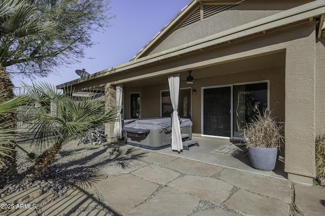 view of patio with ceiling fan and a hot tub