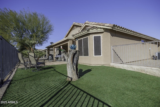 back of house featuring a patio area, a yard, fence, and stucco siding