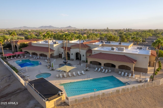 back of property with a patio, a mountain view, a community pool, fence, and stucco siding