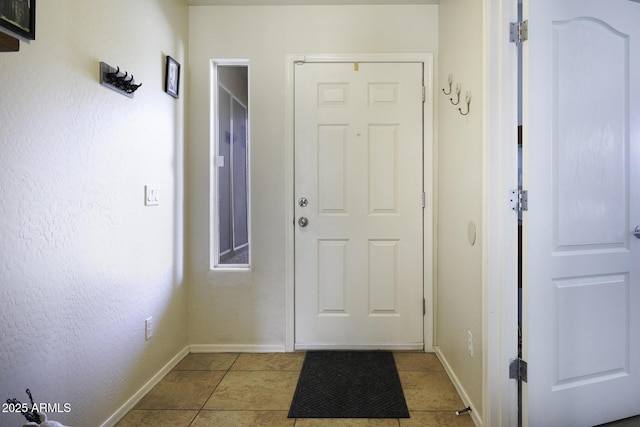 doorway with light tile patterned flooring and baseboards