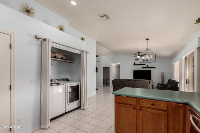 kitchen with vaulted ceiling, washer and dryer, hanging light fixtures, light tile patterned floors, and ceiling fan with notable chandelier