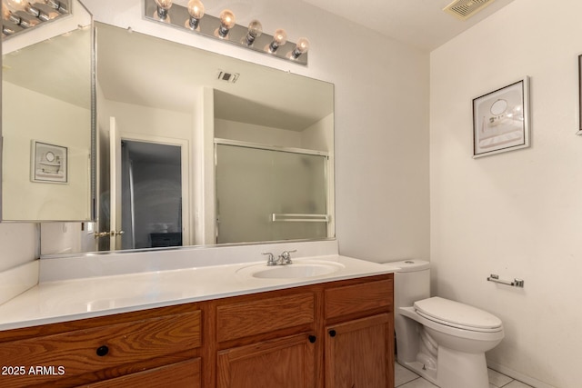 bathroom with a shower with shower door, vanity, tile patterned floors, and toilet