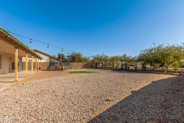 view of yard featuring a trampoline and a patio area