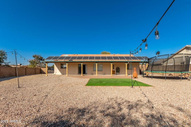 back of house with a trampoline and a patio