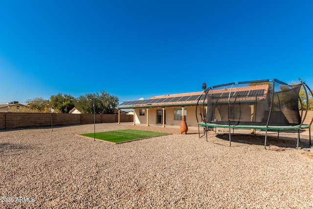 back of property with a trampoline and a patio area