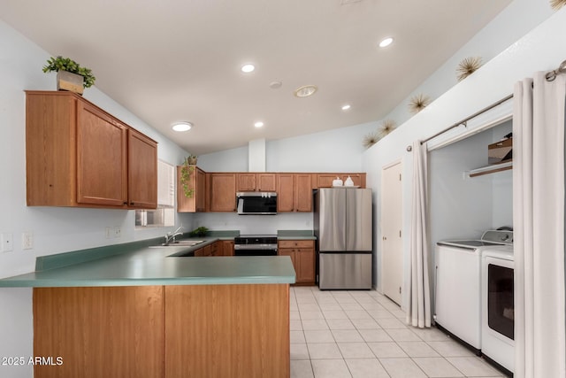 kitchen featuring kitchen peninsula, appliances with stainless steel finishes, separate washer and dryer, light tile patterned flooring, and vaulted ceiling