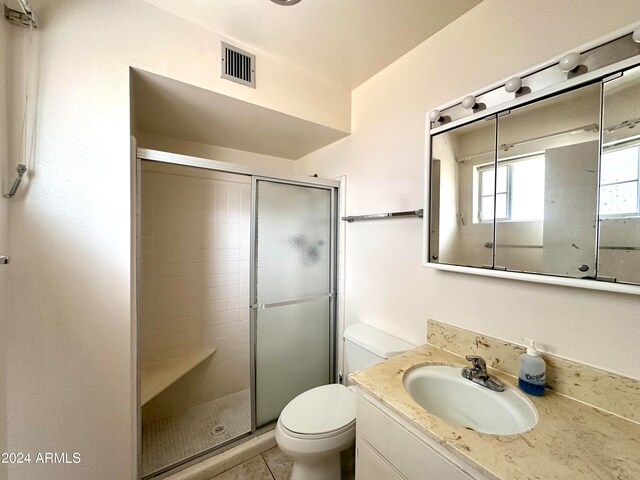 bathroom with tile patterned flooring, vanity, toilet, and a shower with shower door