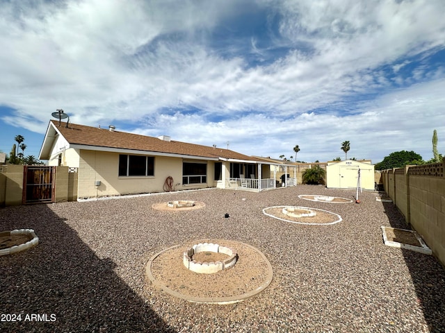 back of house with a fire pit and a storage shed