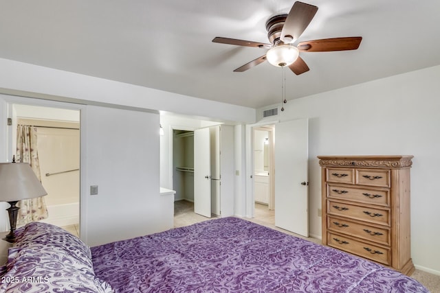 bedroom featuring ceiling fan, a spacious closet, a closet, and ensuite bath