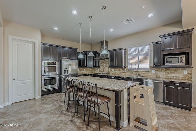 3925 E Elmwood St, Mesa, AZ 85205 - kitchen with appliances with stainless steel finishes, wall chimney exhaust hood, a breakfast bar, a center island, and tasteful backsplash