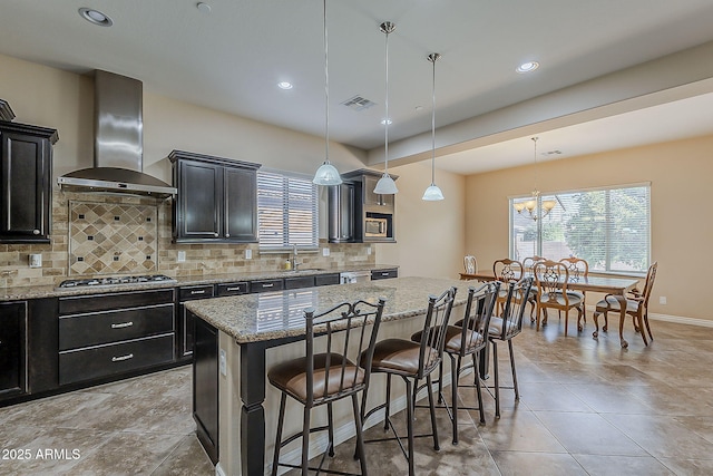 3925 E Elmwood St, Mesa, AZ 85205 - kitchen with wall chimney exhaust hood, healthy amount of natural light, a center island, a breakfast bar area, and recessed lighting