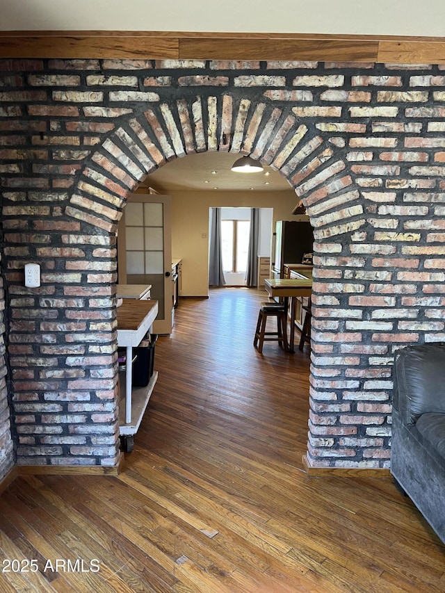 hallway with arched walkways and wood-type flooring