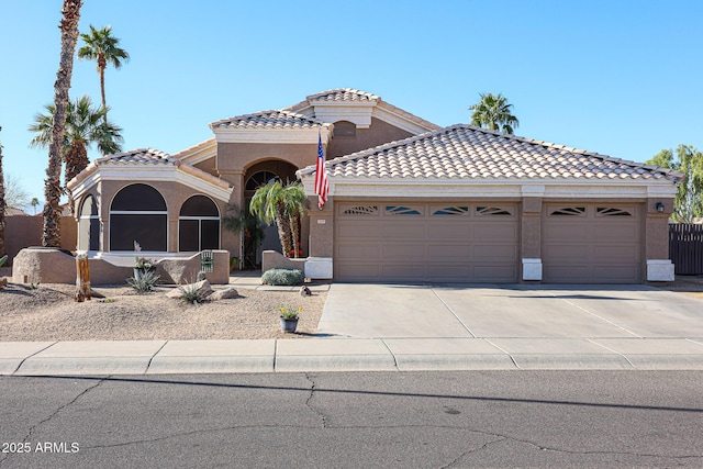 mediterranean / spanish-style house with a tile roof, driveway, an attached garage, and stucco siding