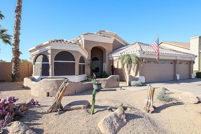 mediterranean / spanish home featuring concrete driveway, an attached garage, a tile roof, and stucco siding